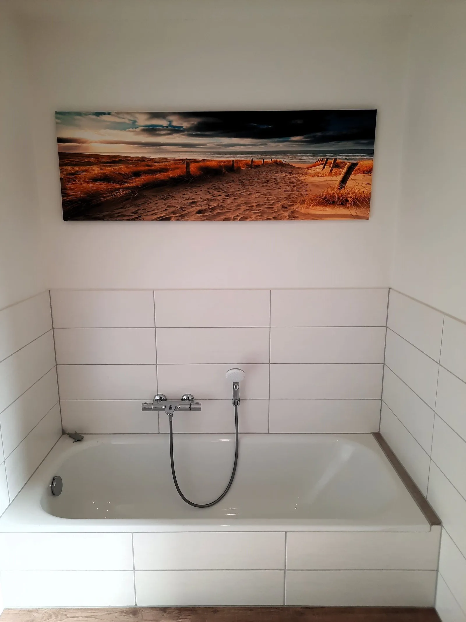Badewanne mit weißen Fliesen und Strandbild
