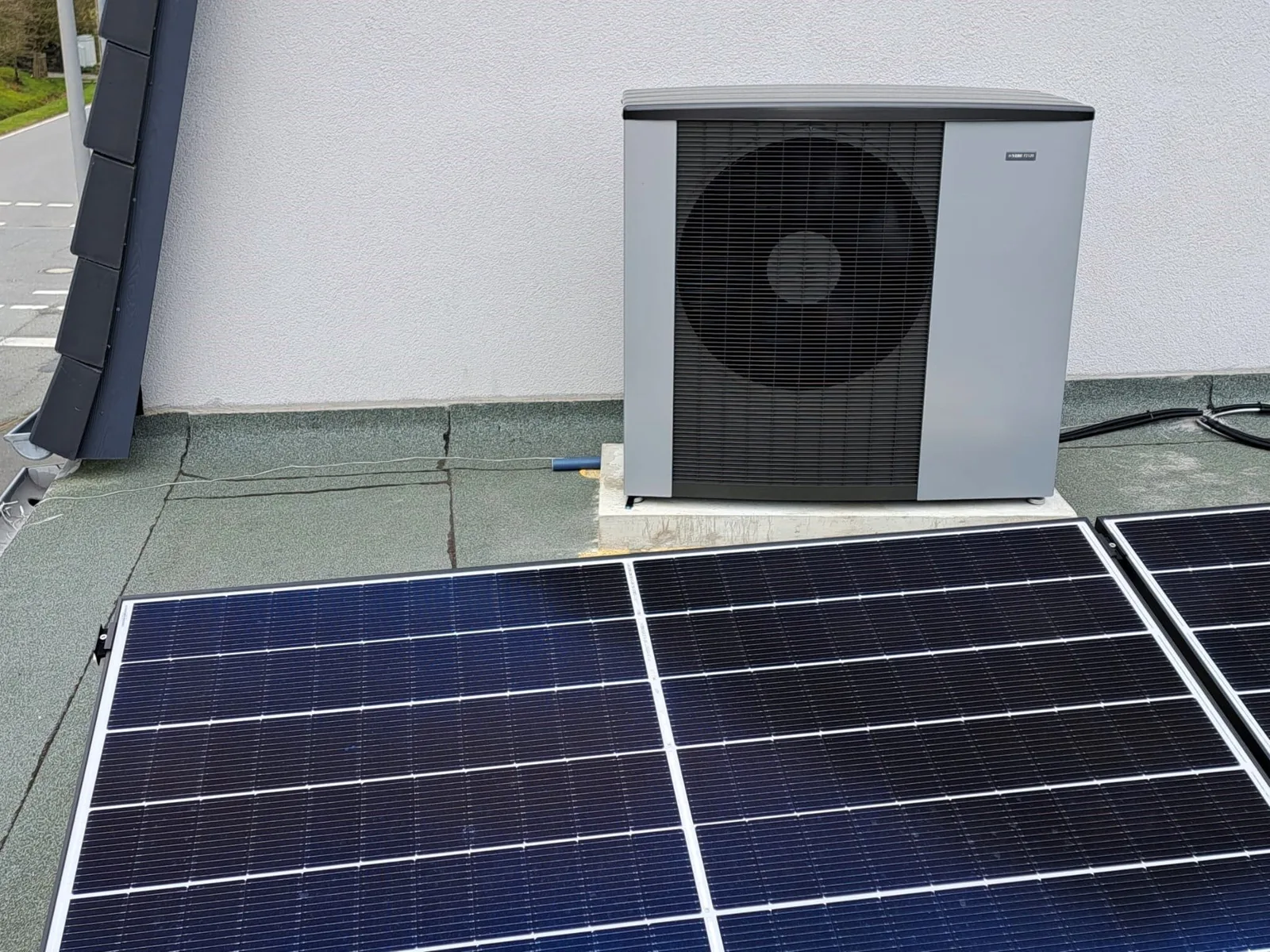 Wärmepumpe auf einem Flachdach neben Photovoltaik-Modulen